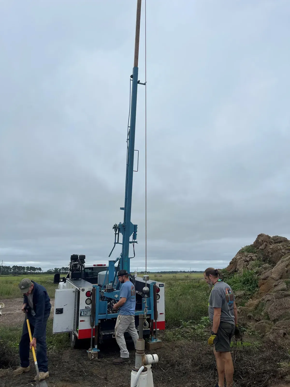 A man is standing next to a crane in a field.
