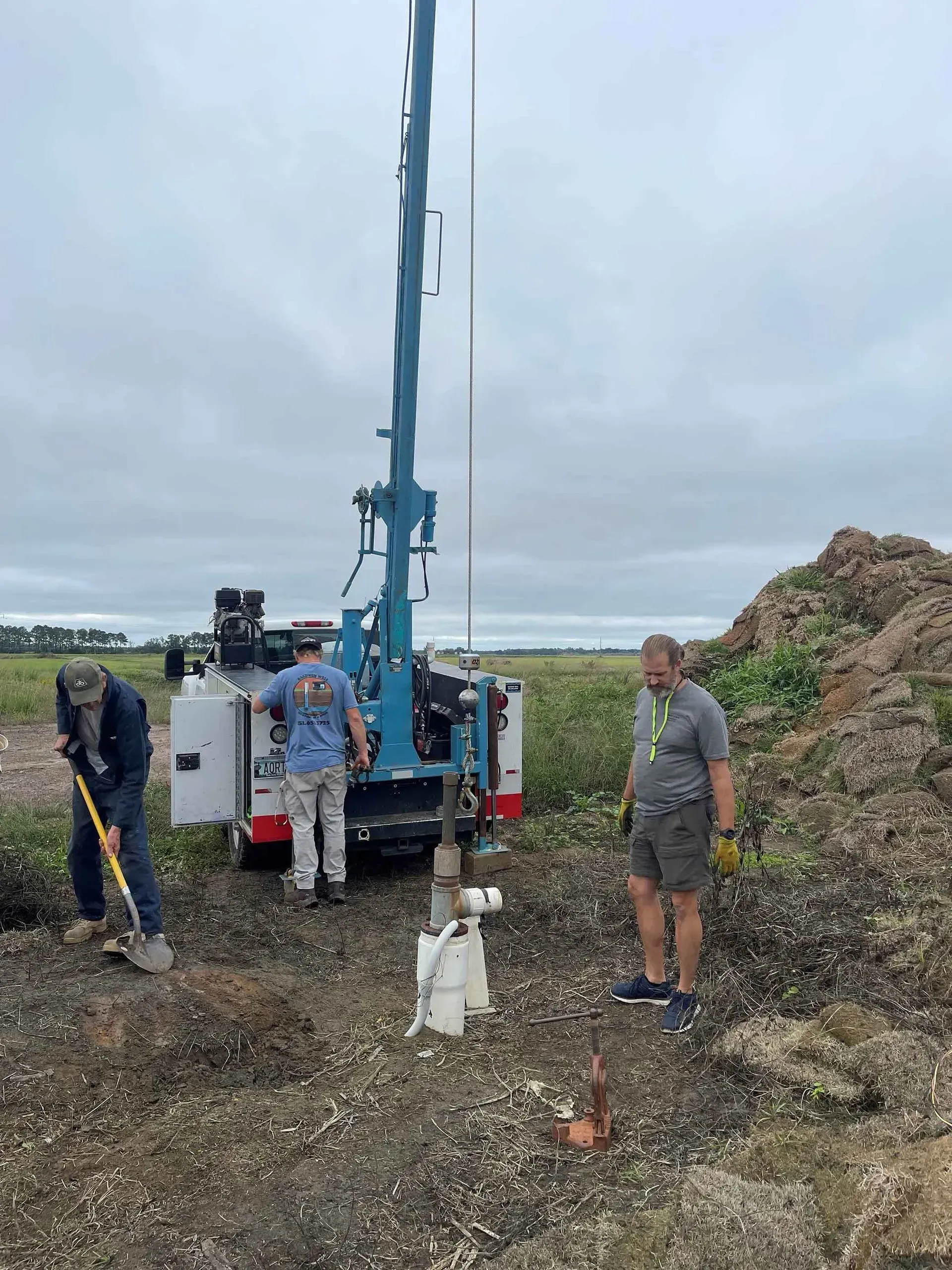 A group of men are working on a drilling rig in a field.