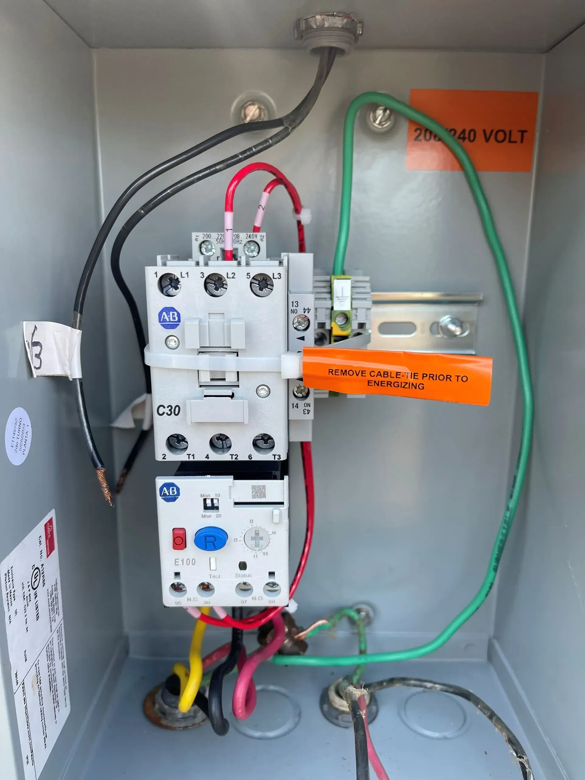 A box with electrical wires and a sticker that says 240 volt