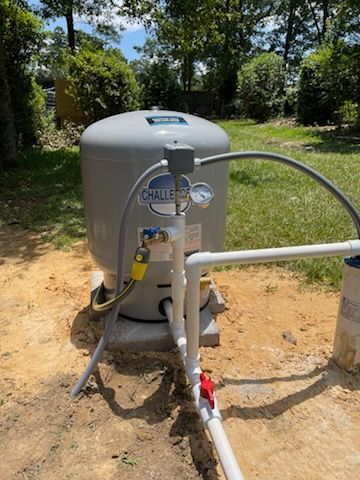 A water pump is sitting in the dirt next to a pipe.