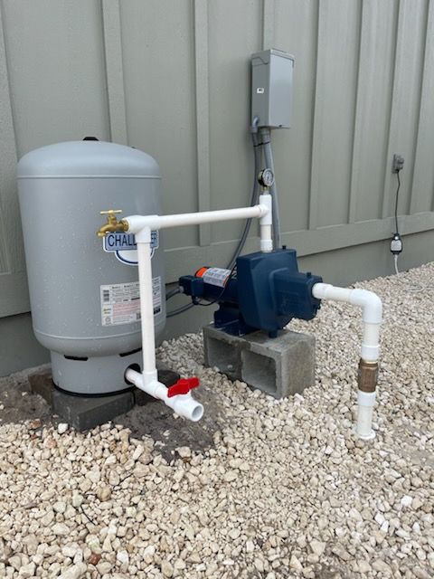 A water pump is attached to a wall next to a water tank.