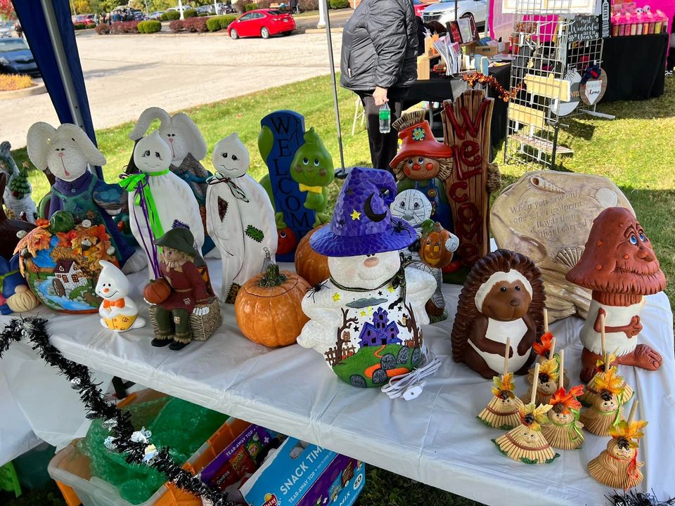 A table displaying various Halloween-themed ceramic decorations at an outdoor market.