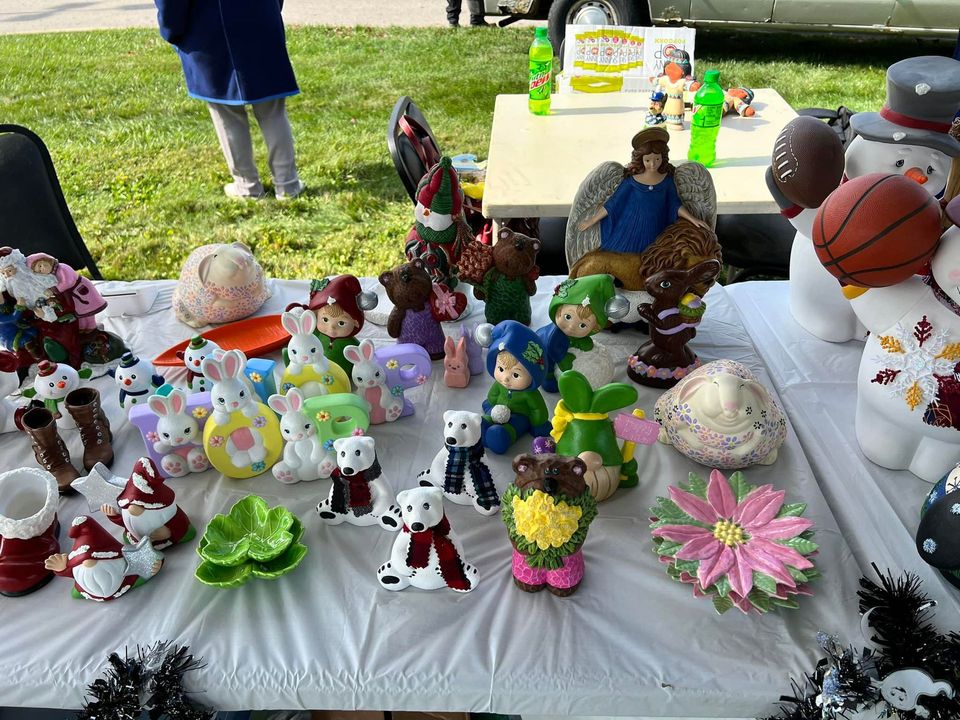 Table of ceramic figurines: bunnies, gnomes, bears, angels, a snowman, and other holiday/seasonal items.
