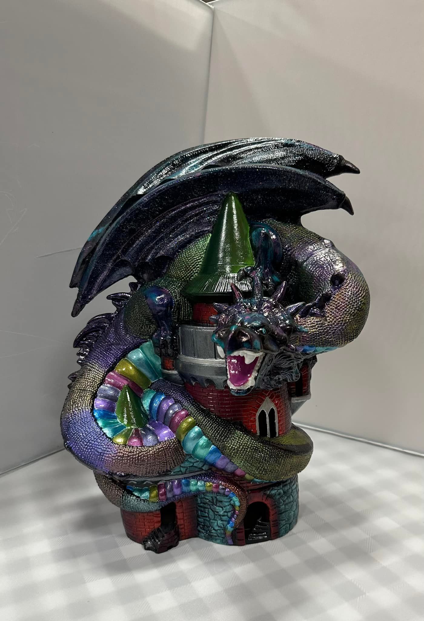 Dragon coiled around a red and gray tower; iridescent scales, black wings.