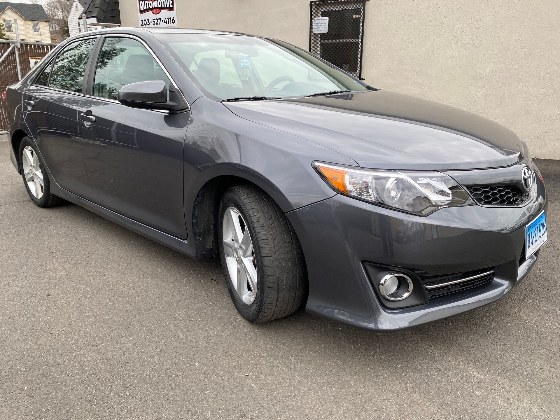 A gray car is parked in front of a building.