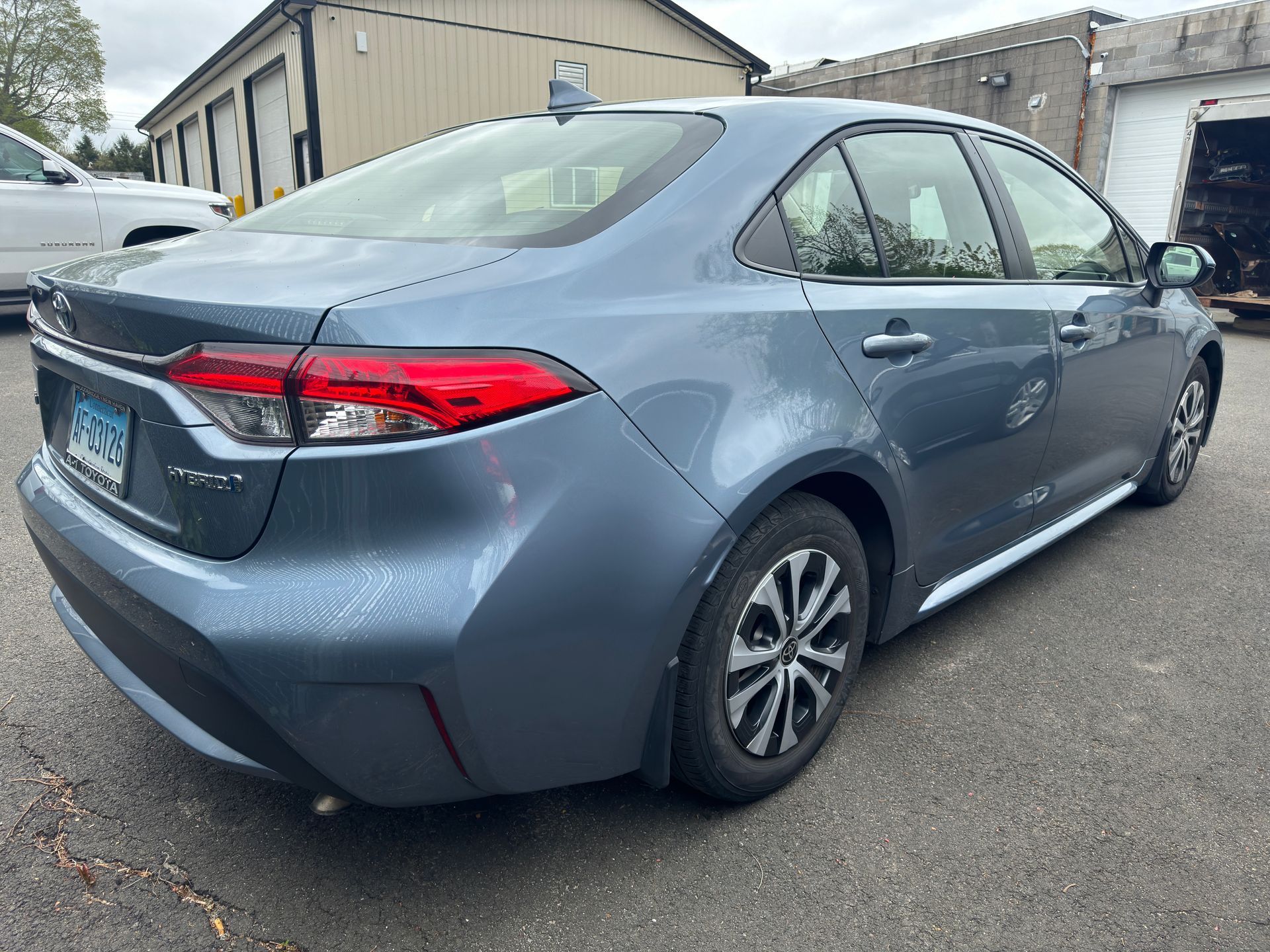 A blue toyota corolla is parked in a parking lot in front of a building.