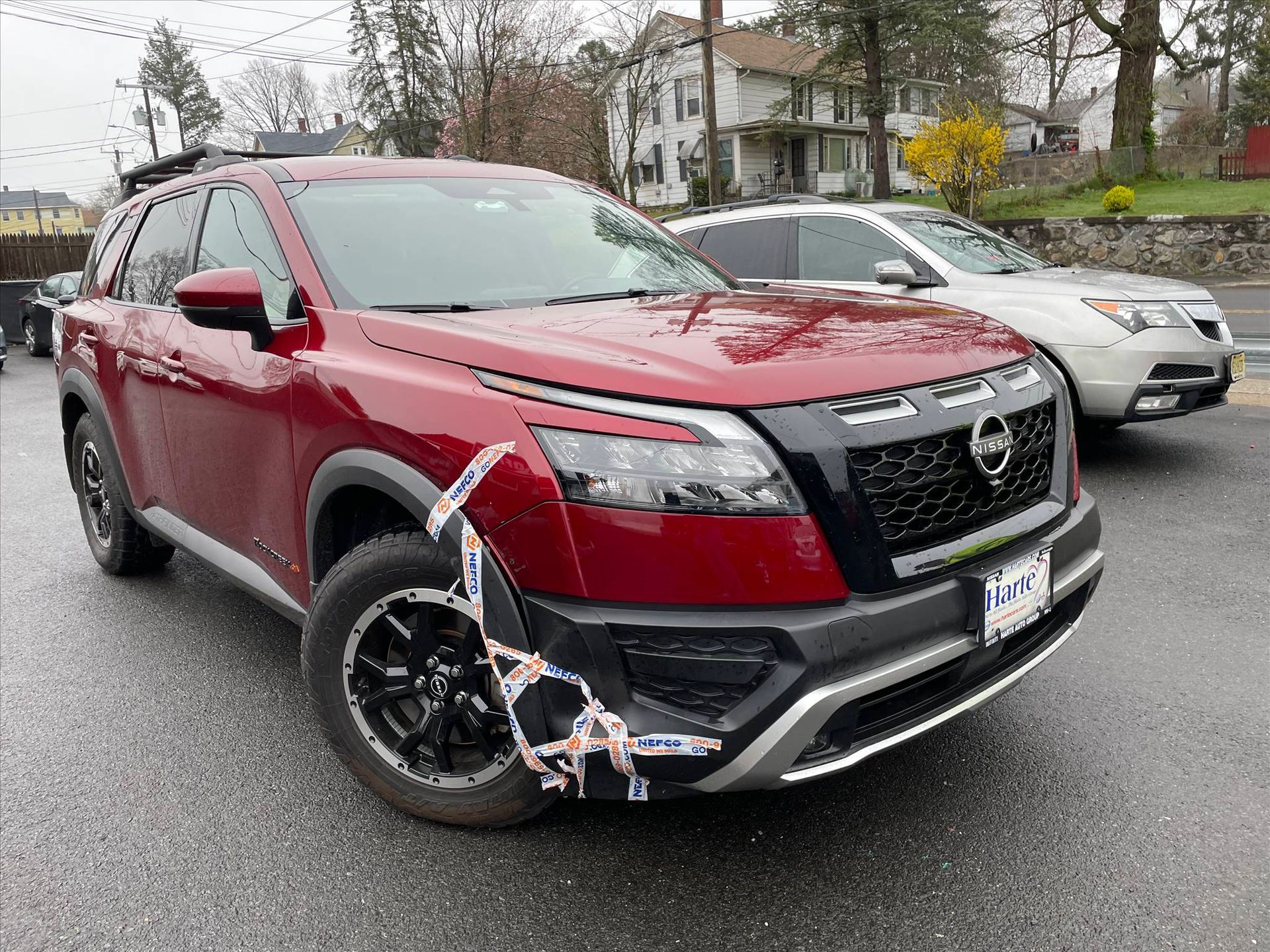 A red nissan rogue suv is parked in a parking lot next to a white suv.