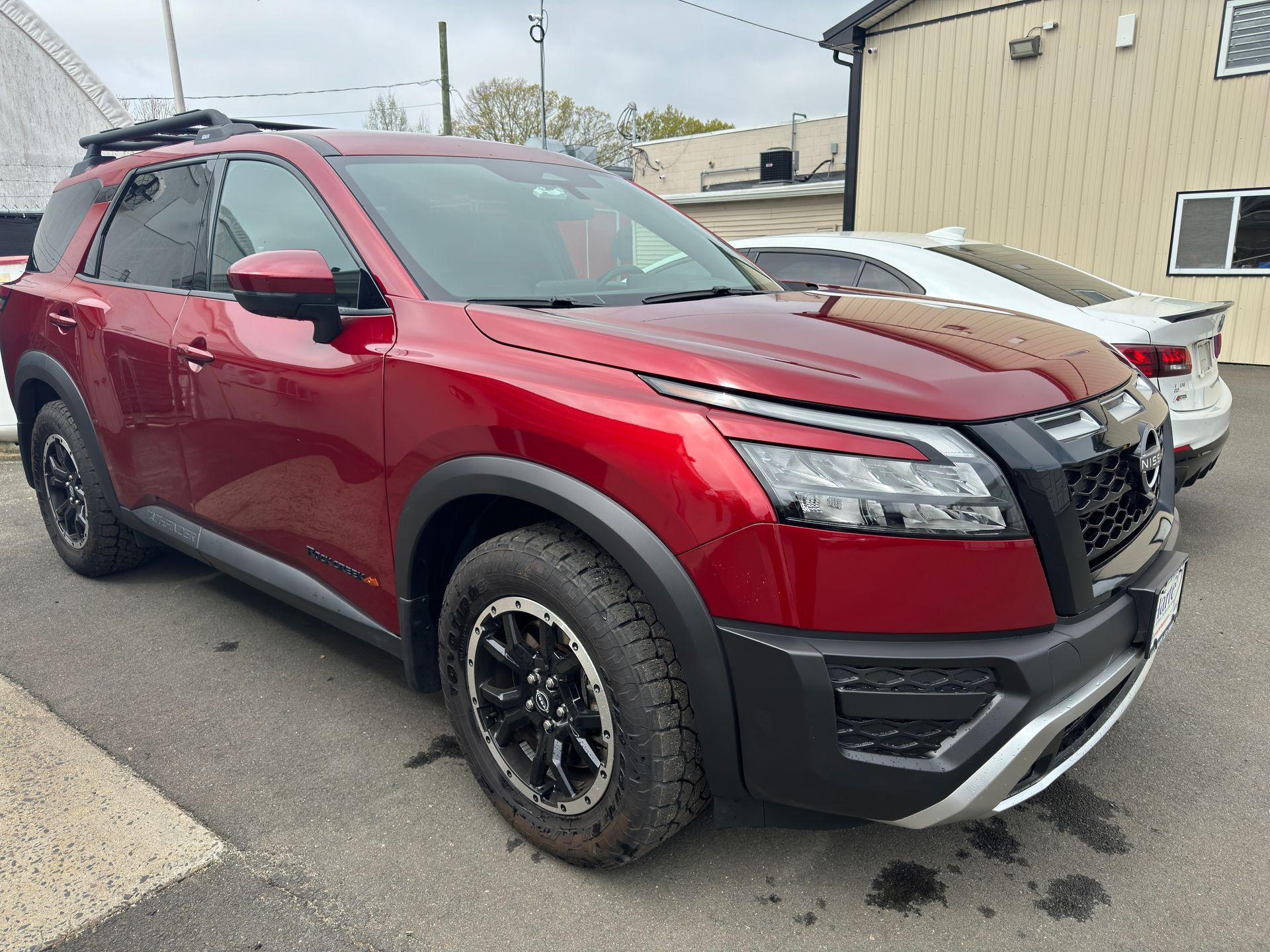 A red nissan pathfinder is parked in front of a building.