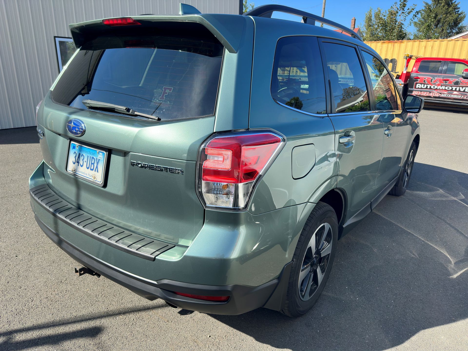 A green subaru forester is parked in a parking lot.