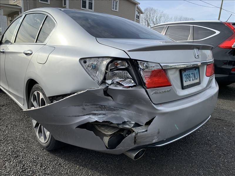 A silver honda accord with a damaged rear end