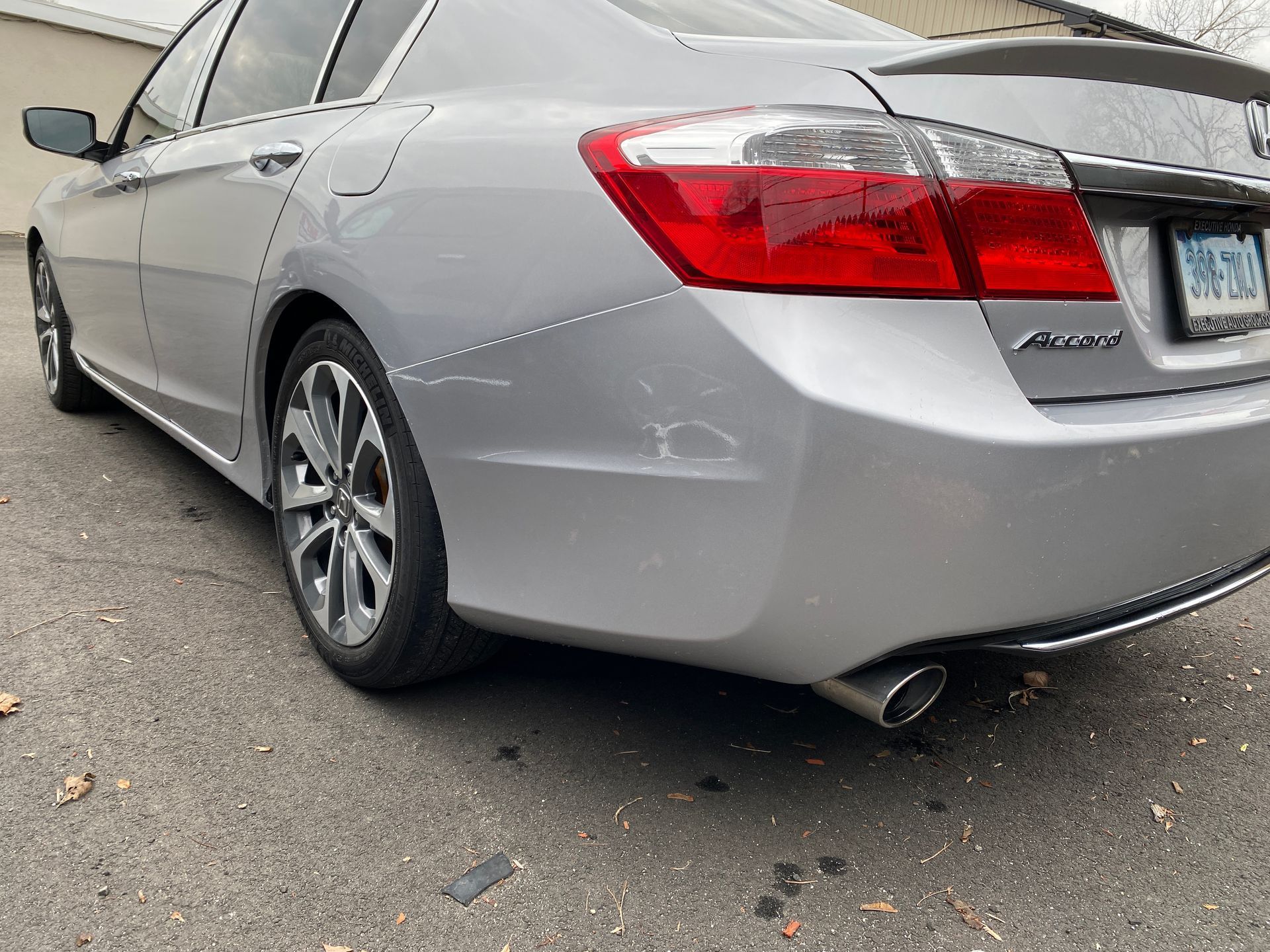 A silver honda accord is parked on the side of the road