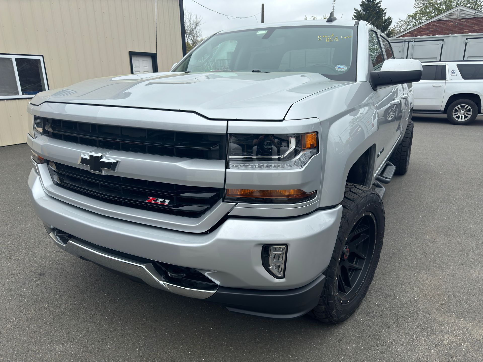 A silver chevrolet silverado truck is parked in front of a building.