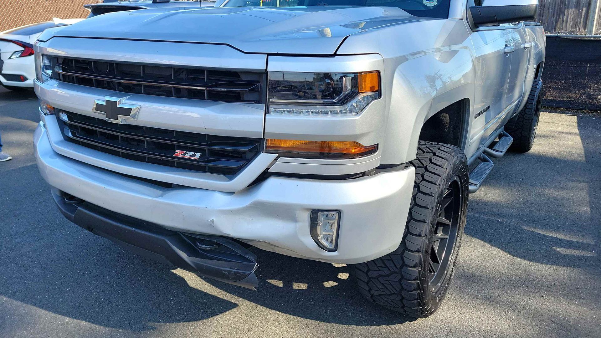 A silver chevrolet silverado truck is parked in a parking lot.