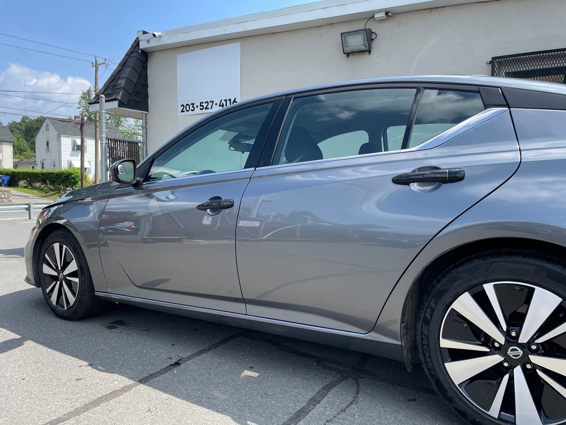 A gray nissan altima is parked in front of a building.