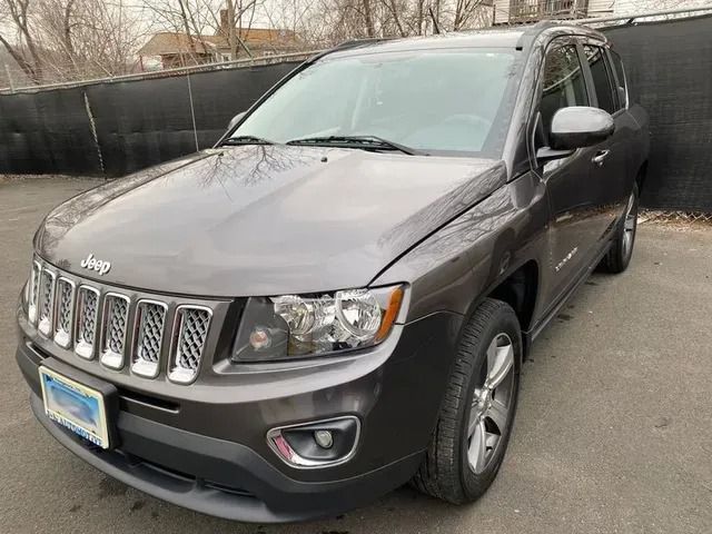 A gray jeep is parked in front of a black fence.