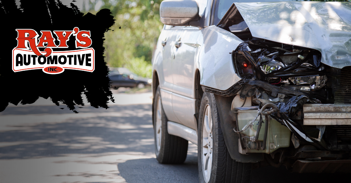 A white vehicle missing its front bumper and grille, revealing the metal frame and radiator, parked outdoors.