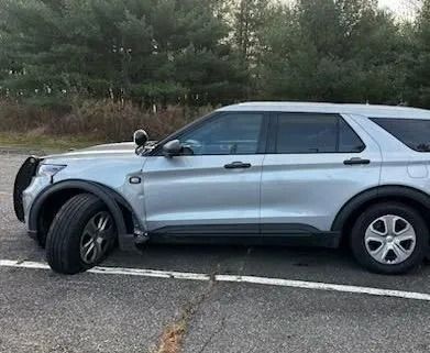 A silver ford explorer police car is parked in a parking lot.