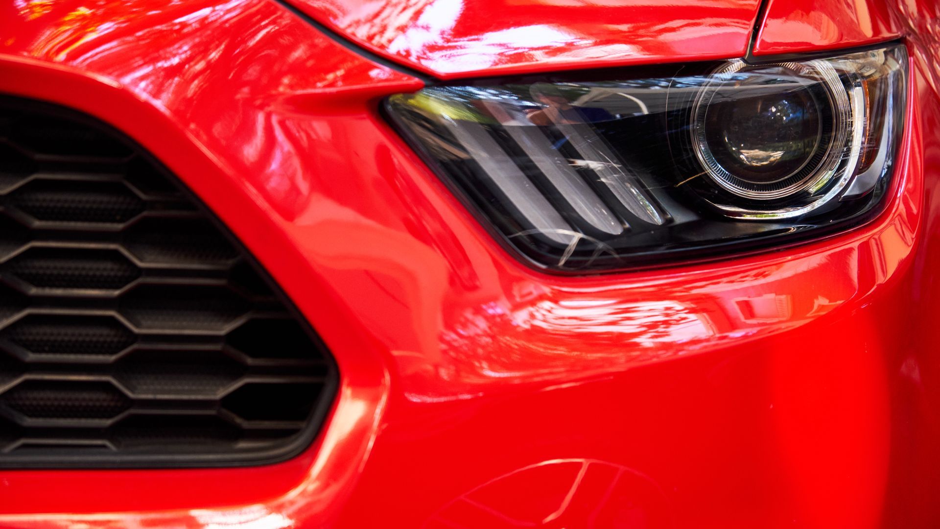 A close up of a red car 's headlight and grille.