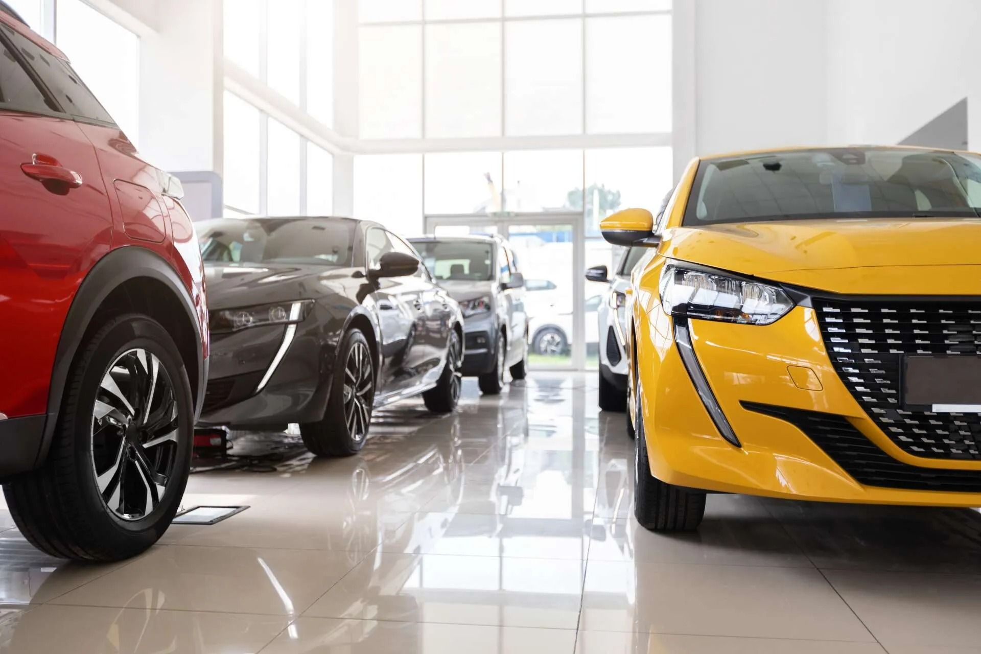 A row of cars are lined up in a showroom.
