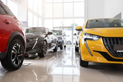 A row of cars are lined up in a showroom.
