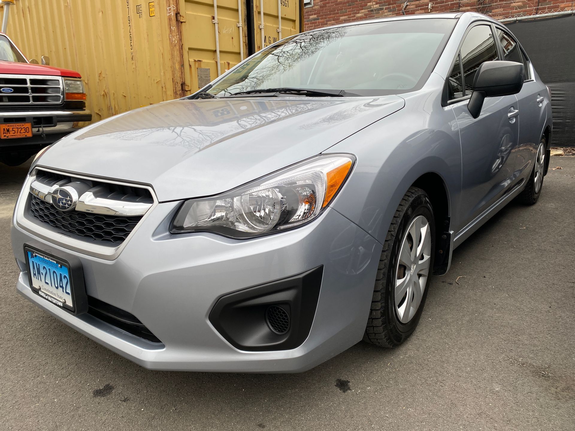 A silver subaru impreza is parked in front of a garge.