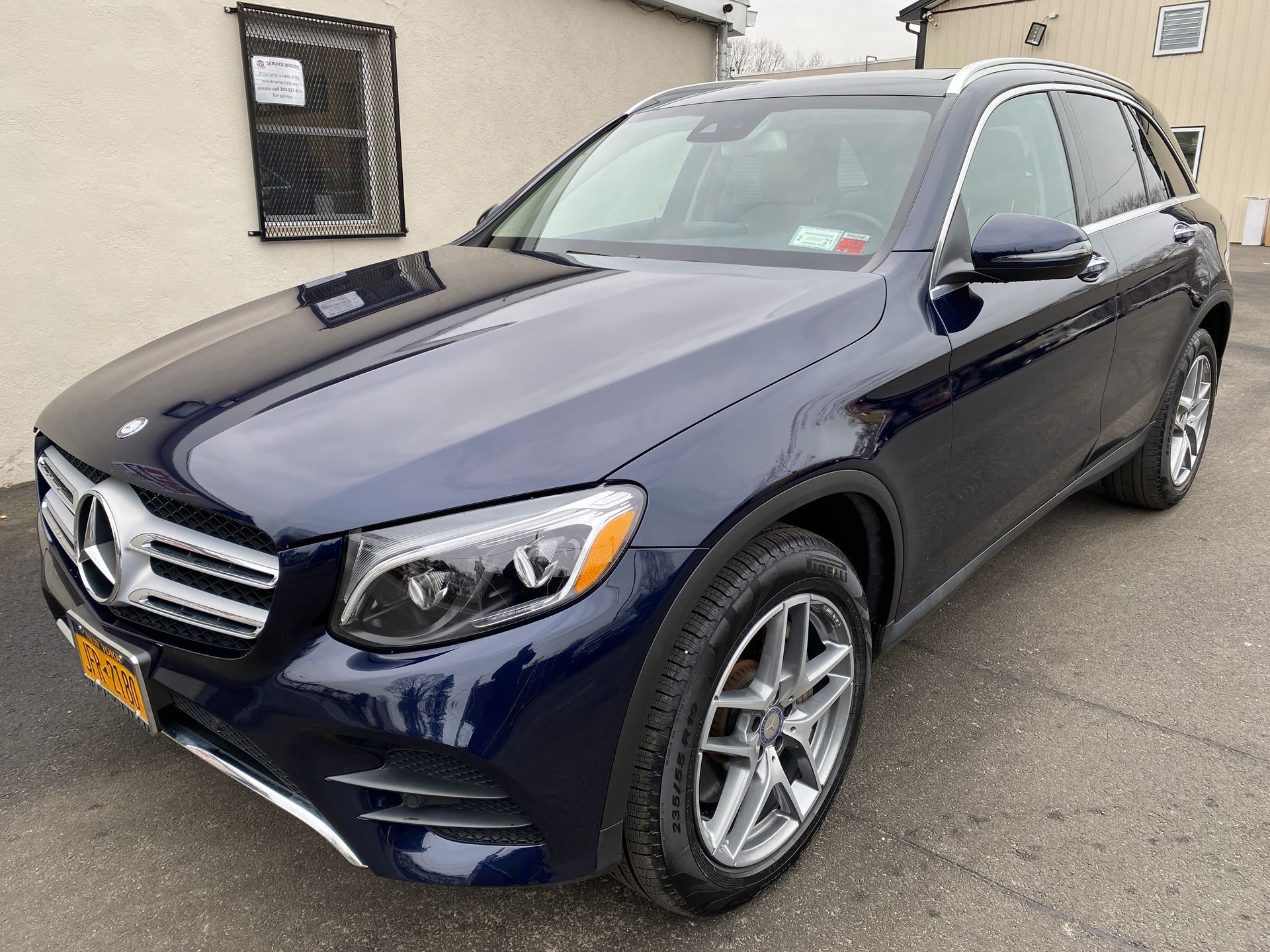 A blue mercedes benz glc is parked in front of a building.