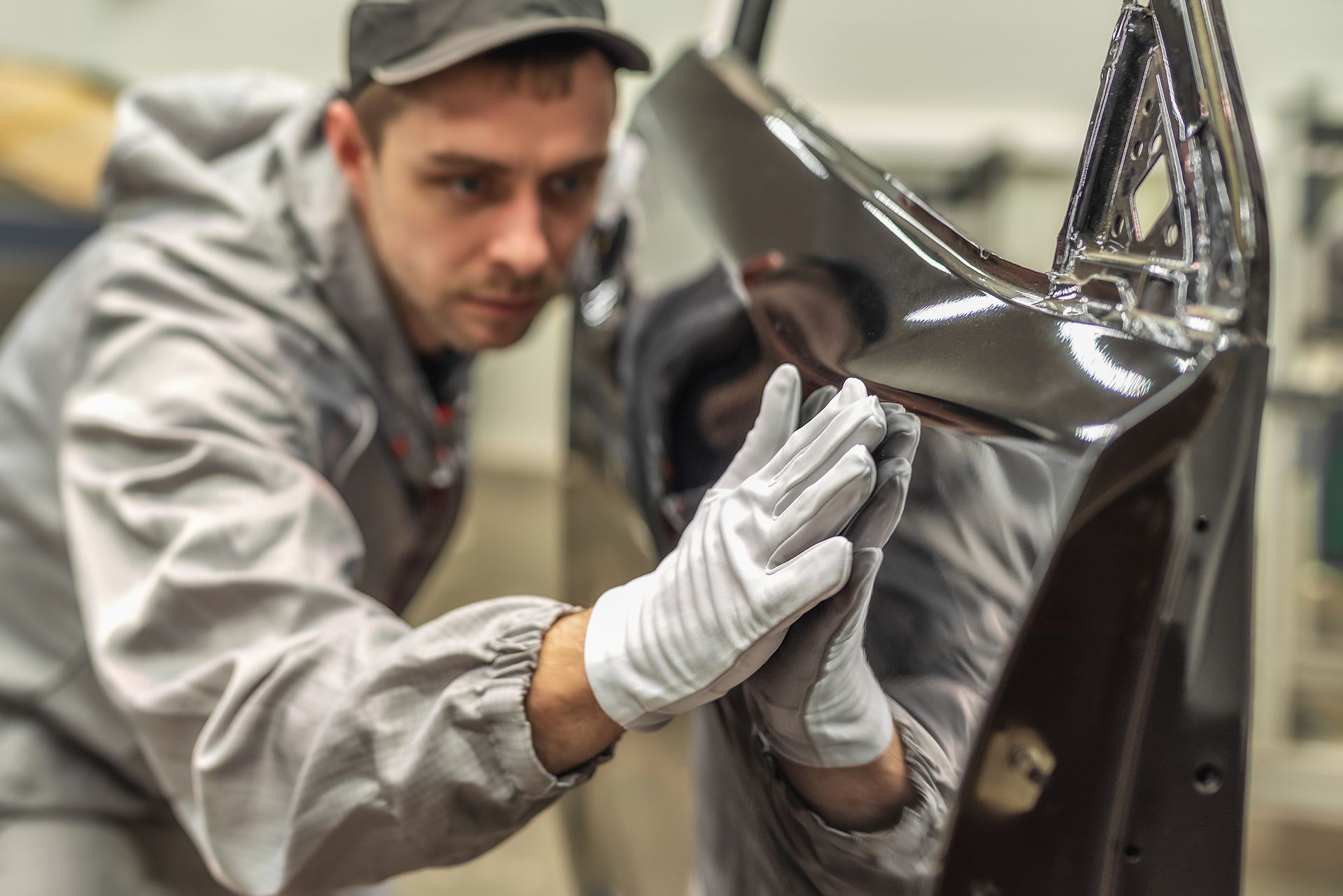 A man wearing white gloves is working on a car door.
