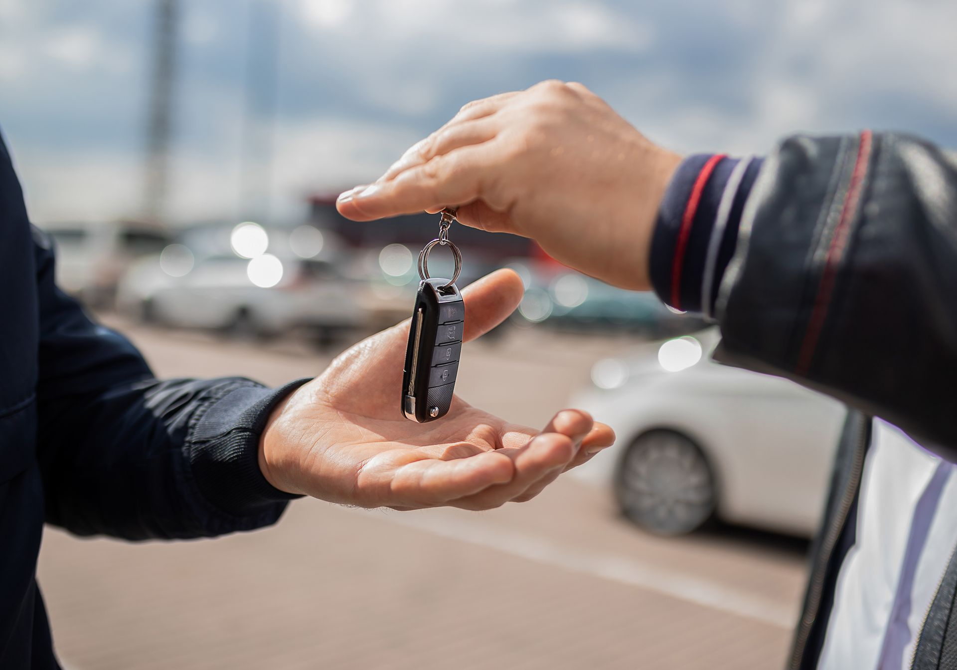 A man is handing a car key to another man.
