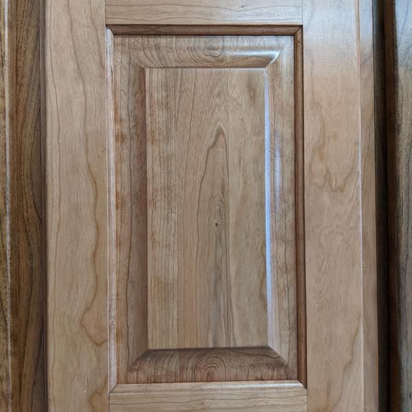 Close-up of a light wood cabinet door with a raised rectangular panel