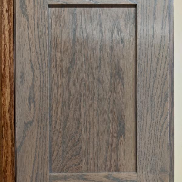 Wooden cabinet door with a rectangular inset panel in a gray-brown finish