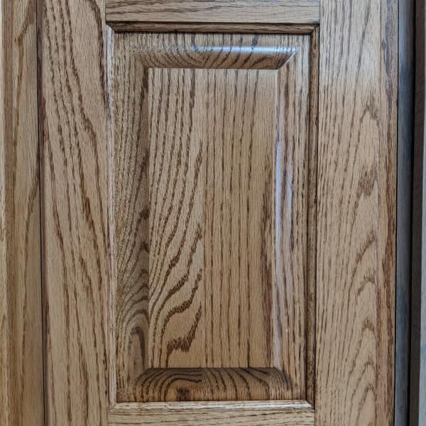 Close-up of a wooden cabinet door with a raised panel design and wood grain finish
