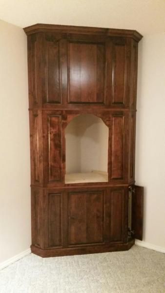 Dark wood corner cabinet with an open center shelf against a beige wall.