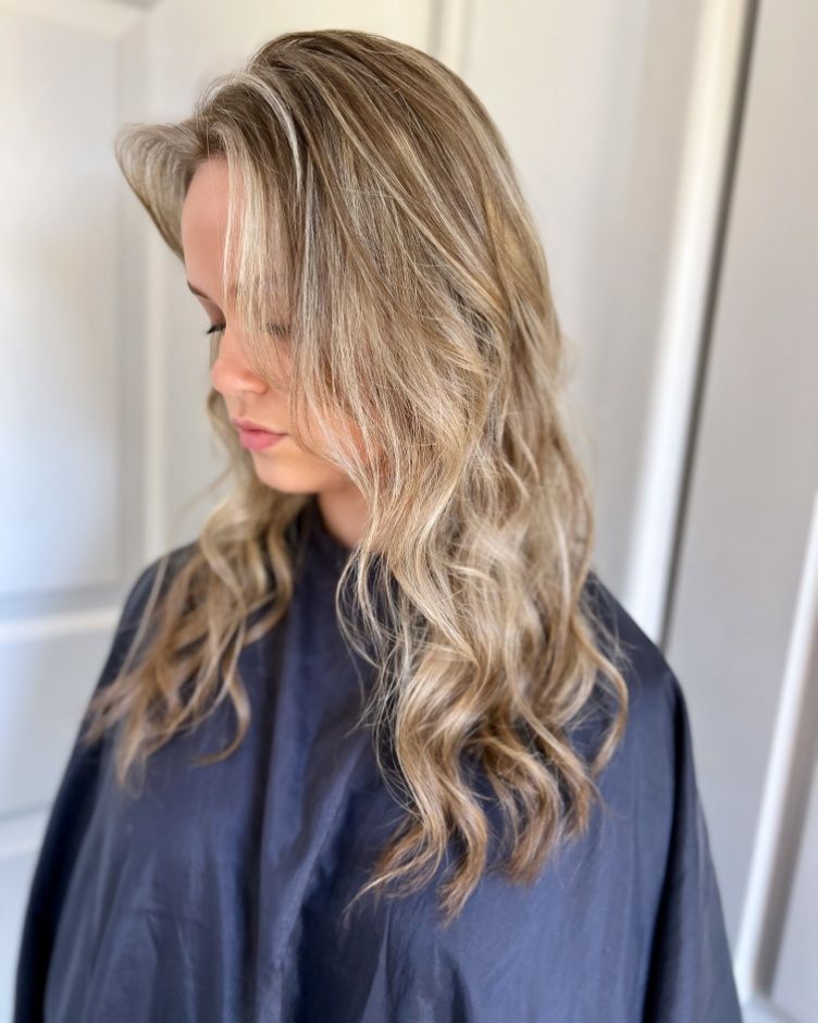 A Woman With Long Blonde Hair Is Wearing A Black Cape — Mjay's Hair Studio & Spa In Dubbo, NSW