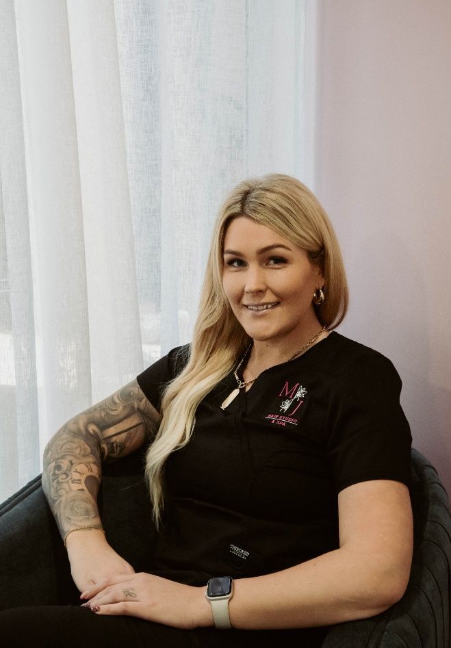 A Woman With Tattoos Is Sitting In A Chair In Front Of A Window — Mjay's Hair Studio & Spa In Dubbo, NSW