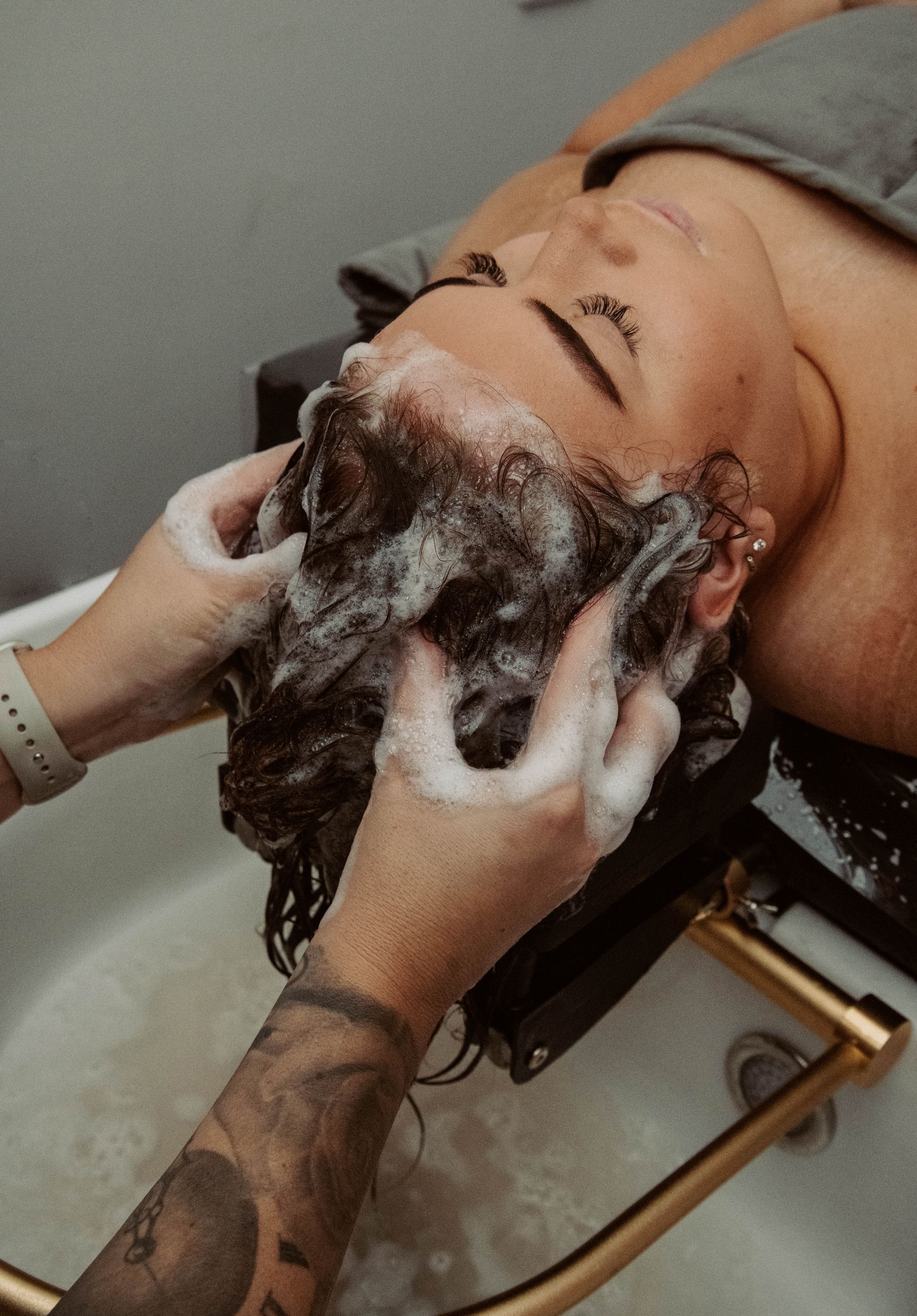A woman is getting her hair washed in a sink at a salon — Mjay's Hair Studio & Spa In Dubbo, NSW