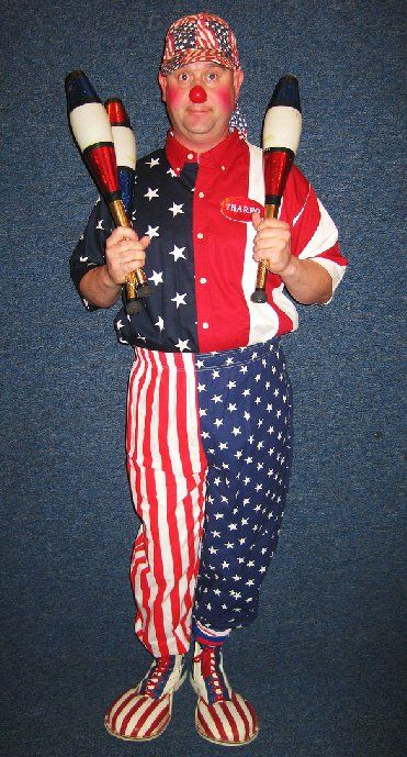 A man dressed as a clown is holding two juggling pins