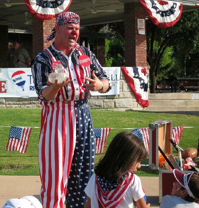 A man in an american flag outfit stands in front of a real estate sign