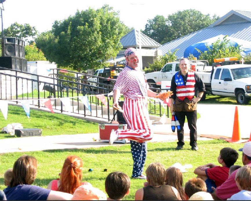 A group of people are watching a clown perform outdoors