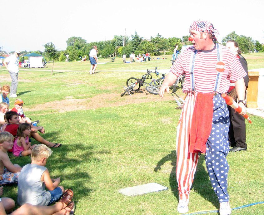 A man in a red white and blue outfit stands in front of a group of children