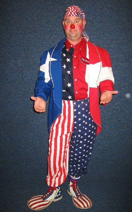 A clown with a red nose is wearing an american flag outfit