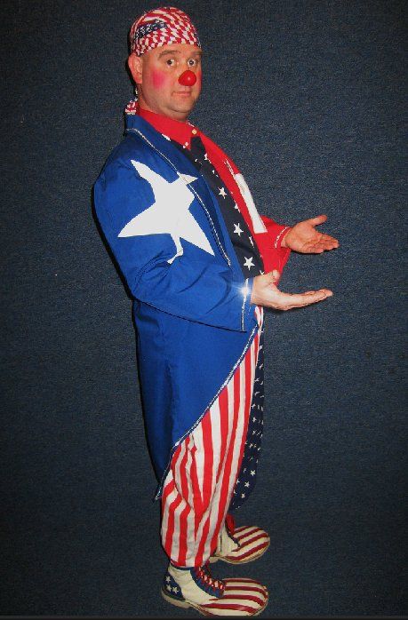 A clown in an american flag costume is standing with his hands outstretched