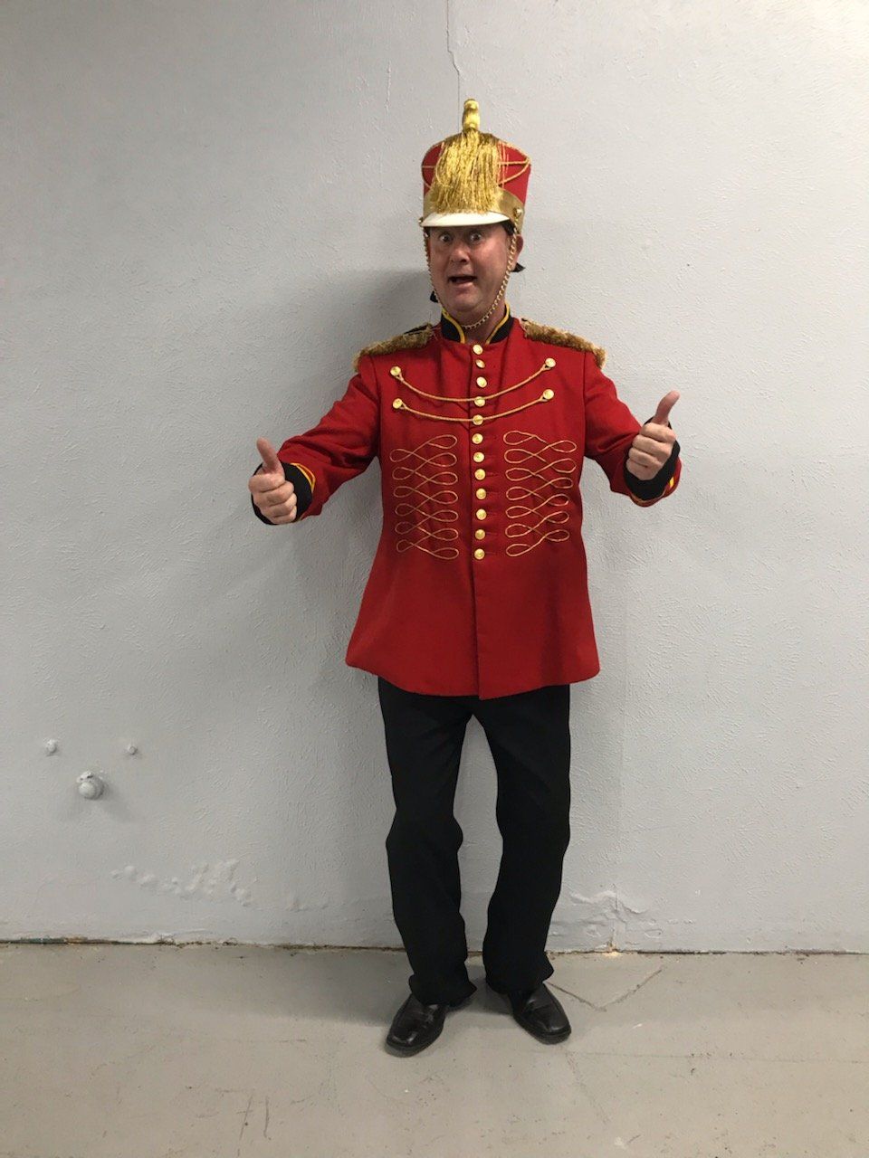 A man in a red military uniform is giving a thumbs up