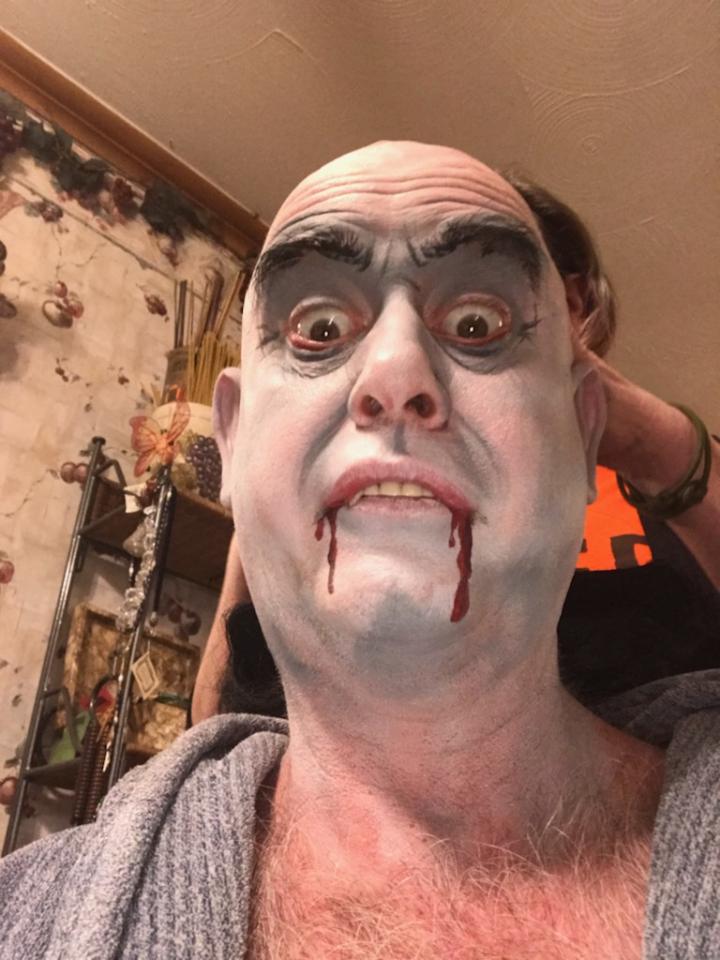 A man is taking a selfie with his face painted like a vampire.