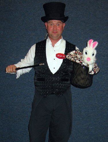 A man in a top hat is holding a rabbit and a wand