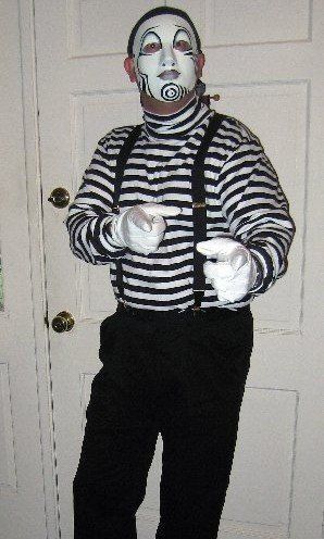 A man in a mime costume is pointing at the camera