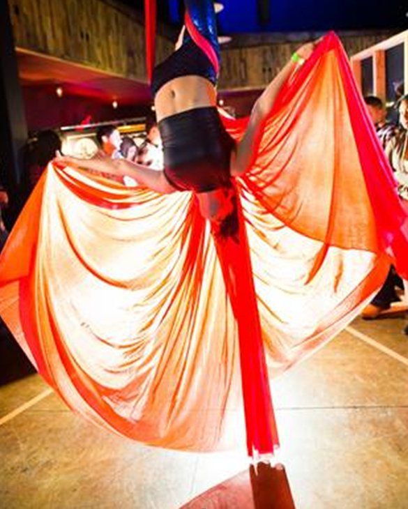 A woman is doing a handstand on a red cloth.