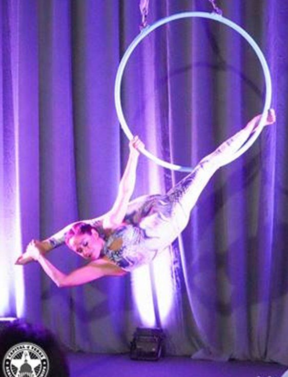 A woman is performing aerial acrobatics on an aerial hoop.