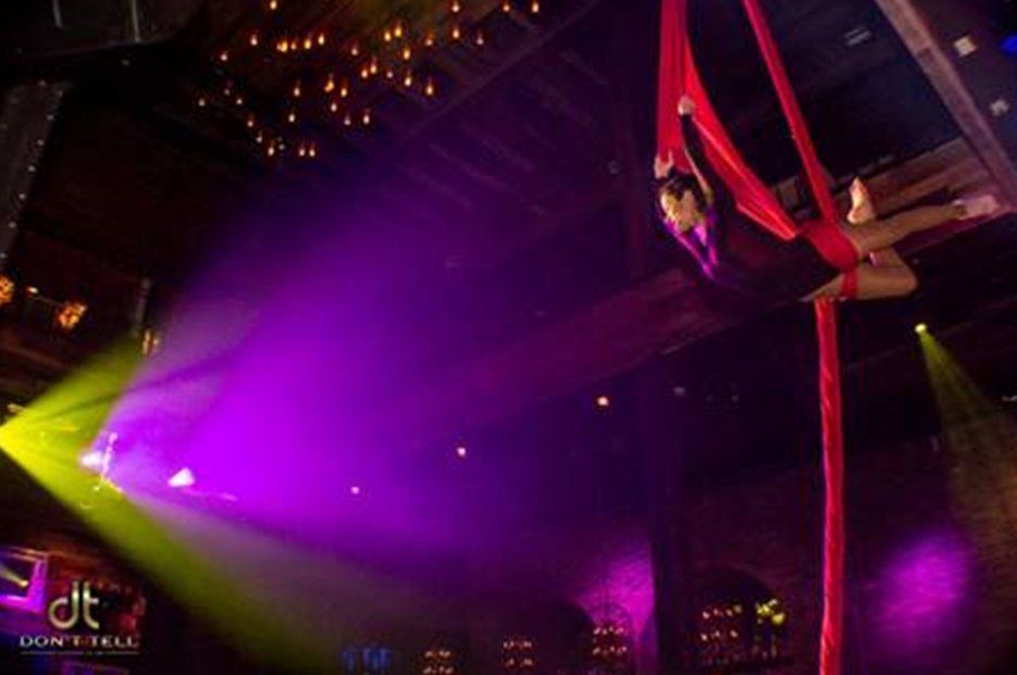 A woman is performing aerial acrobatics in a dark room.