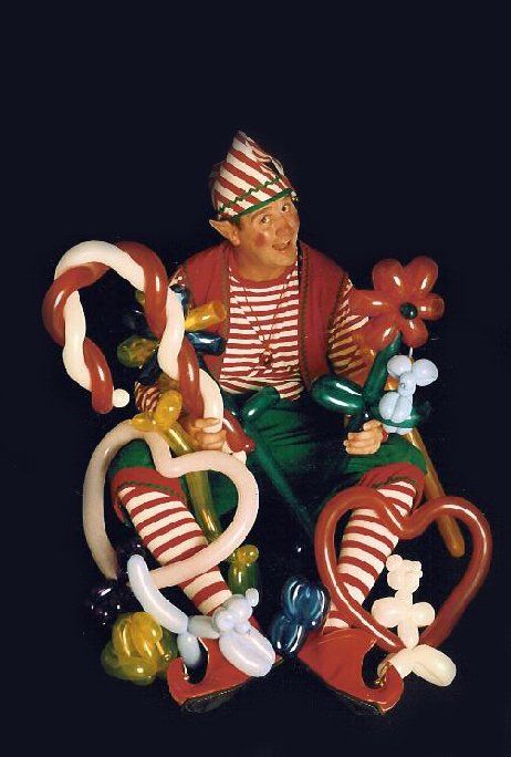 A clown is sitting on a pile of balloons and candy canes