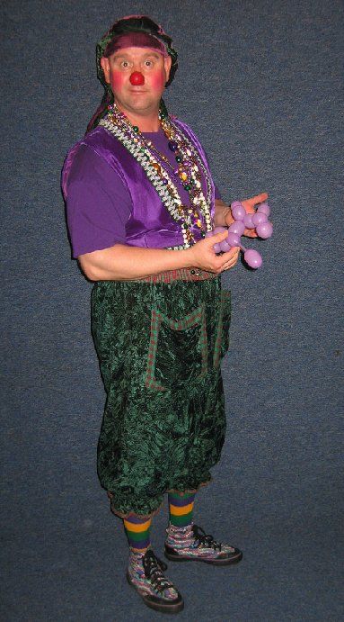 A man dressed as a clown is holding purple balloons.